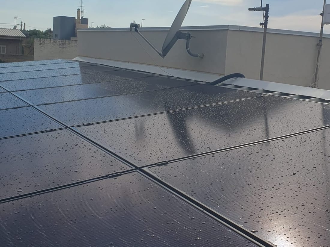 Pannelli fotovoltaici visti da vicino dopo la pioggia, con le gocce e il riflesso del sole